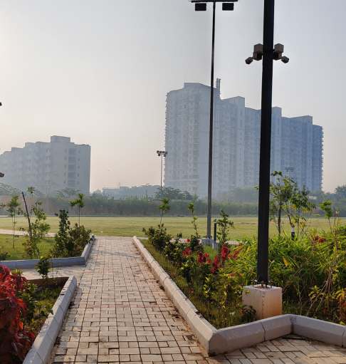 Green landscaped park with walking pathway and sports court at Bollineni Zion